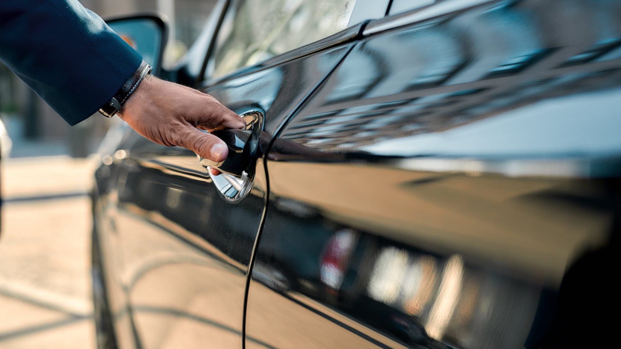 Hand am Türgriff einer schwarzen Limousine